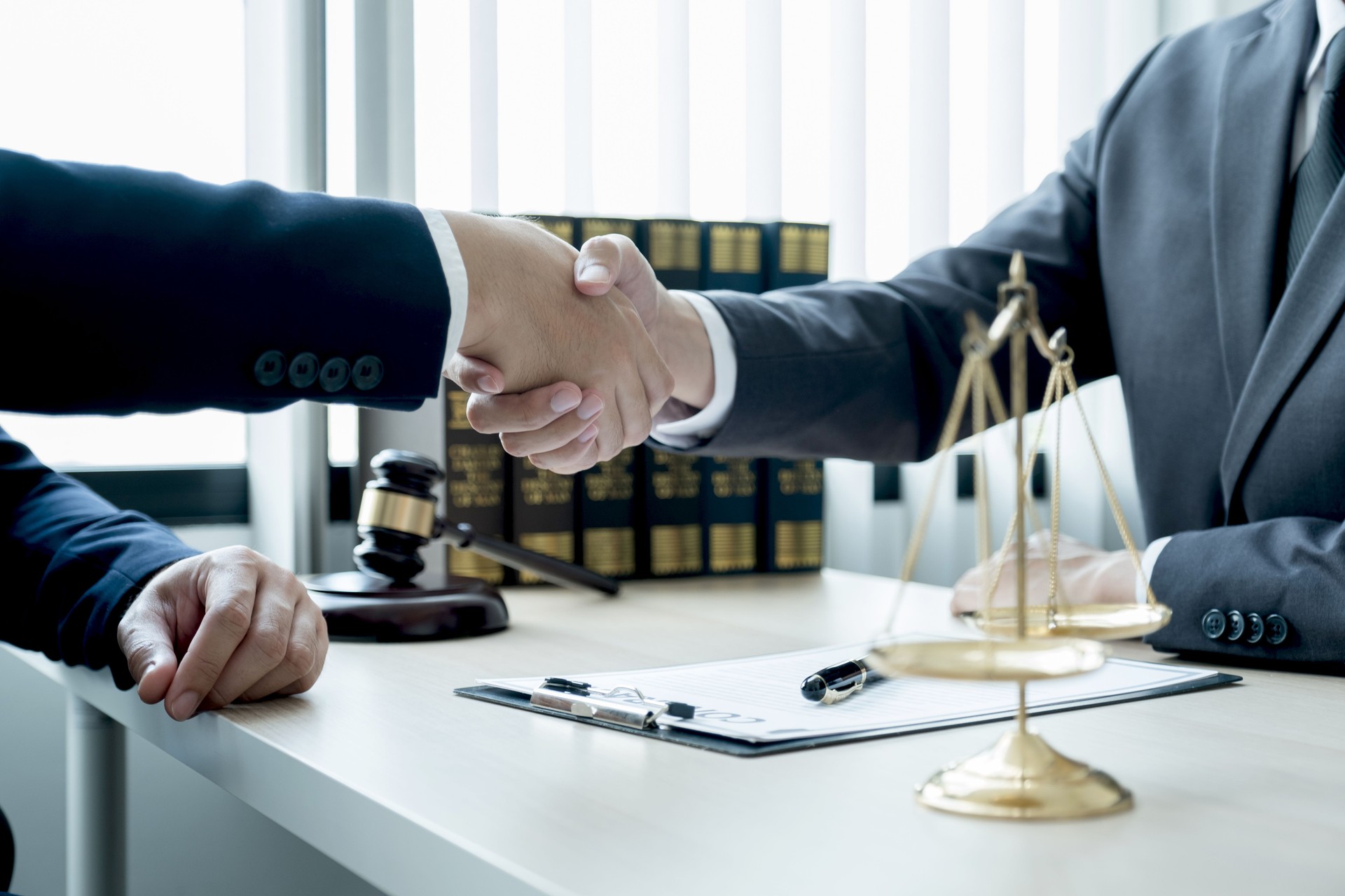 Handshake after Lawyer  providing legal consult business dispute service to the man at the office with justice scale and gavel hammer